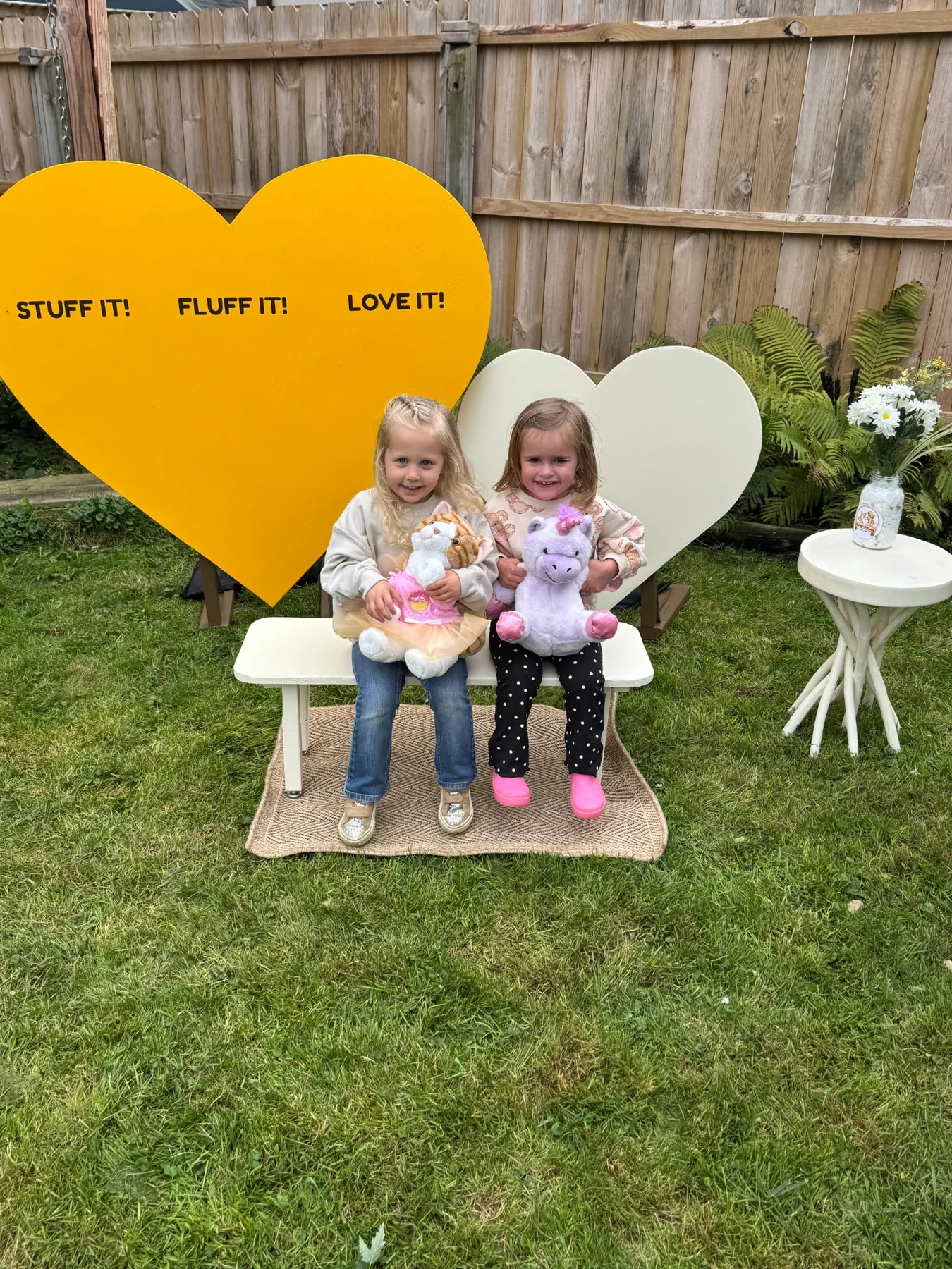 Two children holding their finished Stuffed With Love plush friends at the Stuff It, Fluff It, Love It heart photo spot